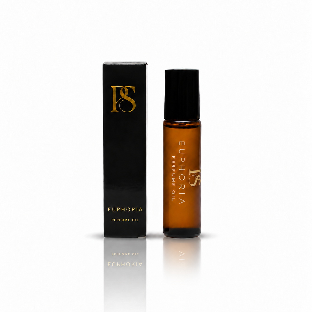 A bottle of Euphoria Perfume Oil next to its black packaging box with gold lettering, displayed on a clean white background with a soft reflection.